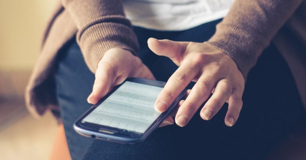 Close-up of adult using smartphone indoors, browsing web with focus on screen.