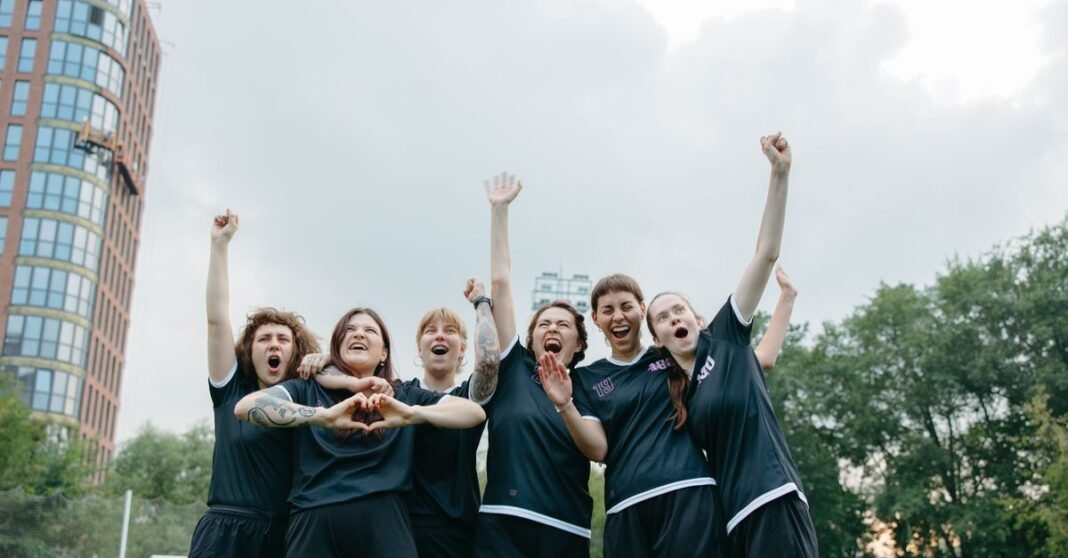 A joyful group of women soccer players celebrating victory on the field.