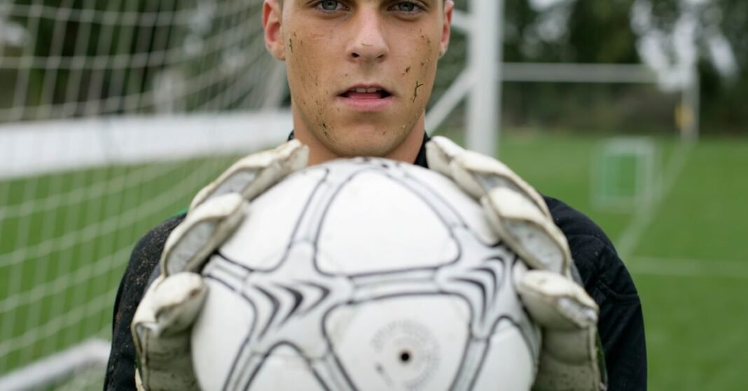 Focused soccer goalkeeper holding the ball confidently on the field.