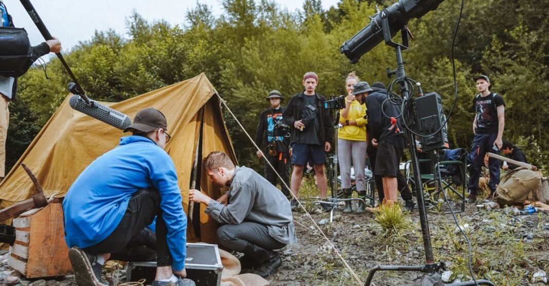 Film crew setting up an outdoor scene with a tent and professional gear.