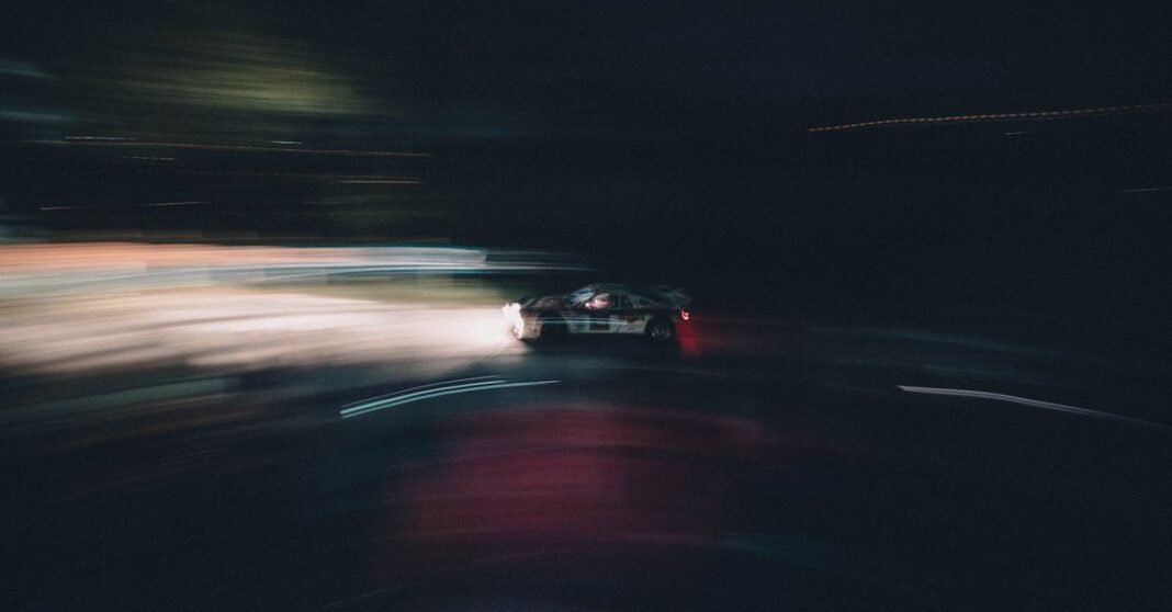Blurred race car speeding on a night track in San Marino, capturing motion and excitement.