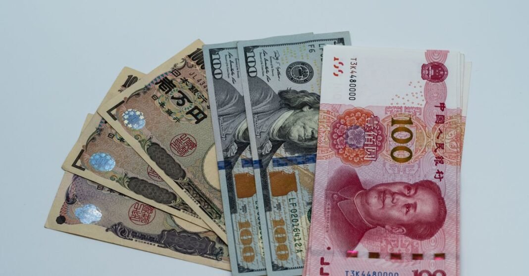 Various international currency notes including US dollars, yen, and yuan arranged on a surface.