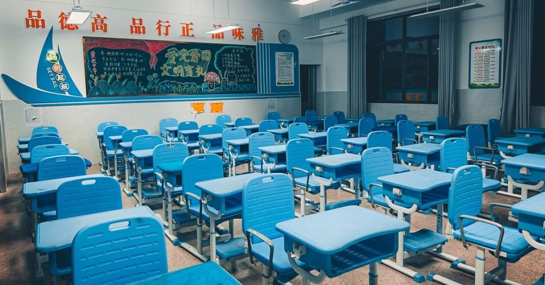 Spacious classroom with blue desks and vibrant decorated chalkboard, ready for students.