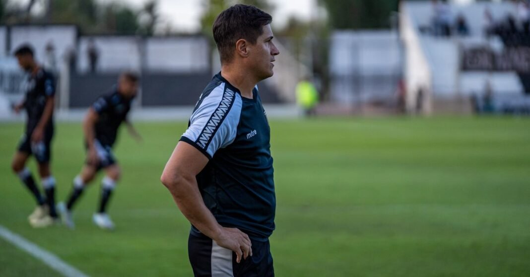Soccer coach observing match strategy during an outdoor game.