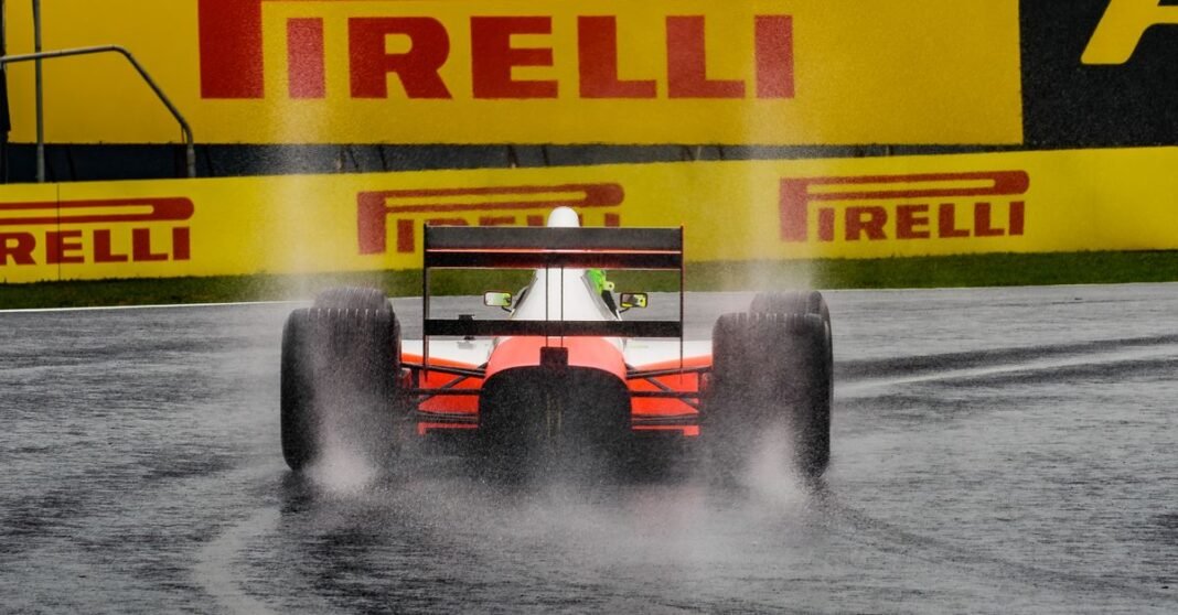 A Formula One car splashes through a wet track under a prominent Pirelli sign.