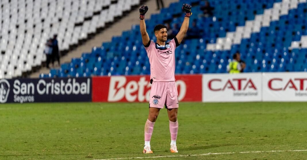 Footballer in pink uniform celebrating a victory in an empty stadium.