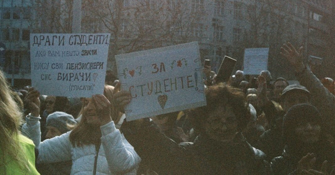 A large group of students holding signs during a peaceful protest outdoors.