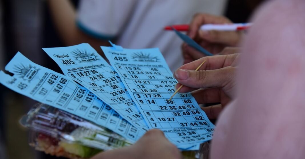 People playing bingo indoors, holding blue bingo cards with pen and markers.
