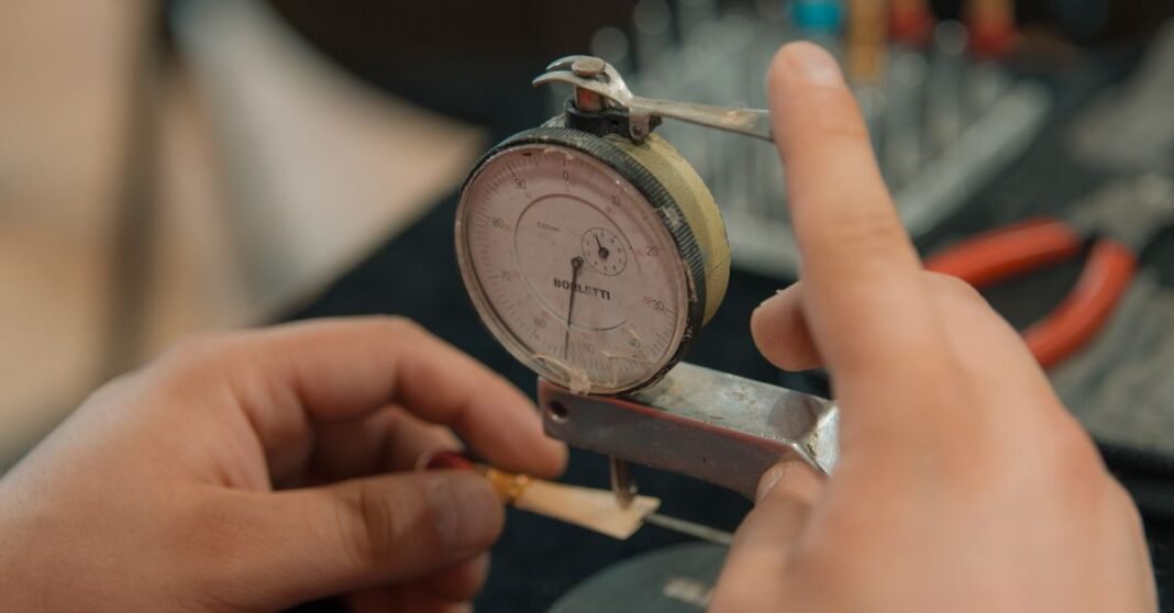 Hands measuring with an analog dial indicator for precision work.
