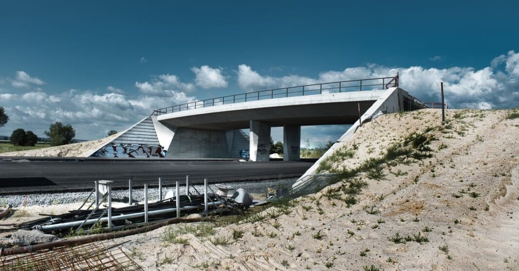 A modern overpass under construction with clear blue skies and natural surroundings.