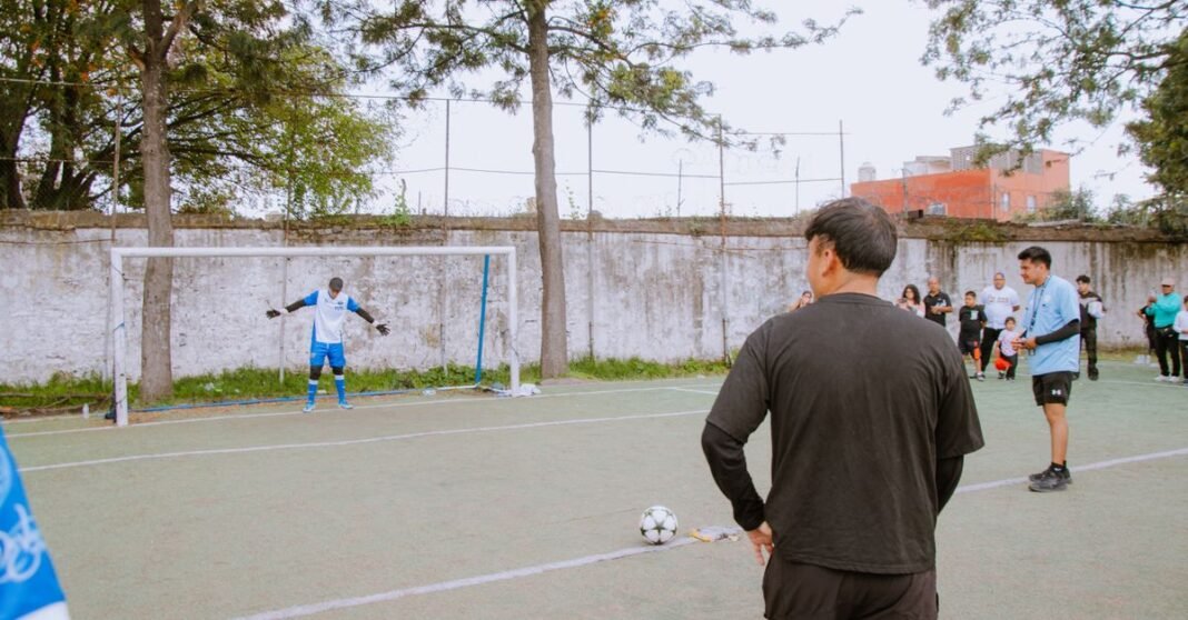 Amateur soccer game with players preparing for a penalty kick on a community field.