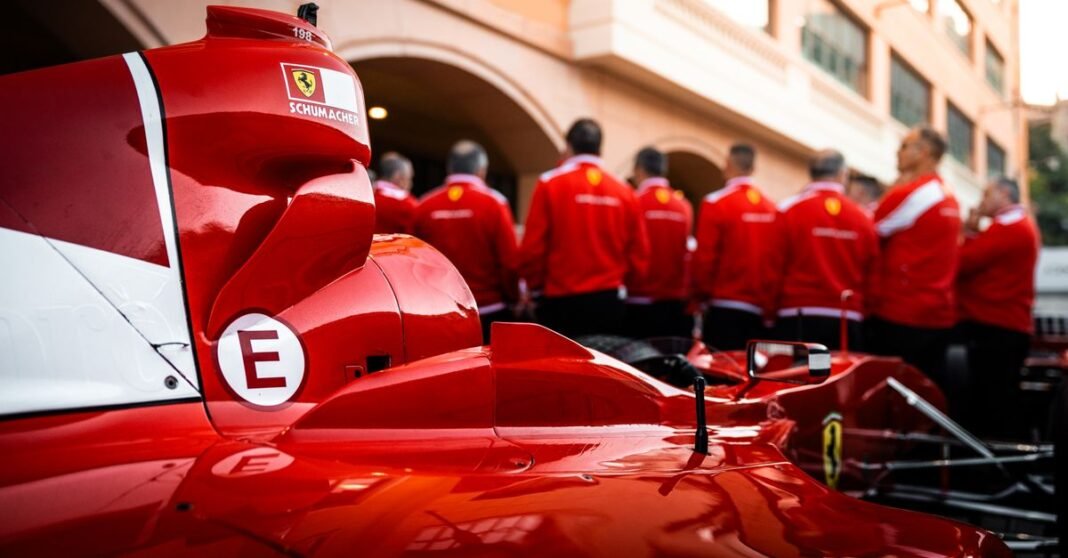 Close-up of a red Formula 1 car with team members in matching uniforms.