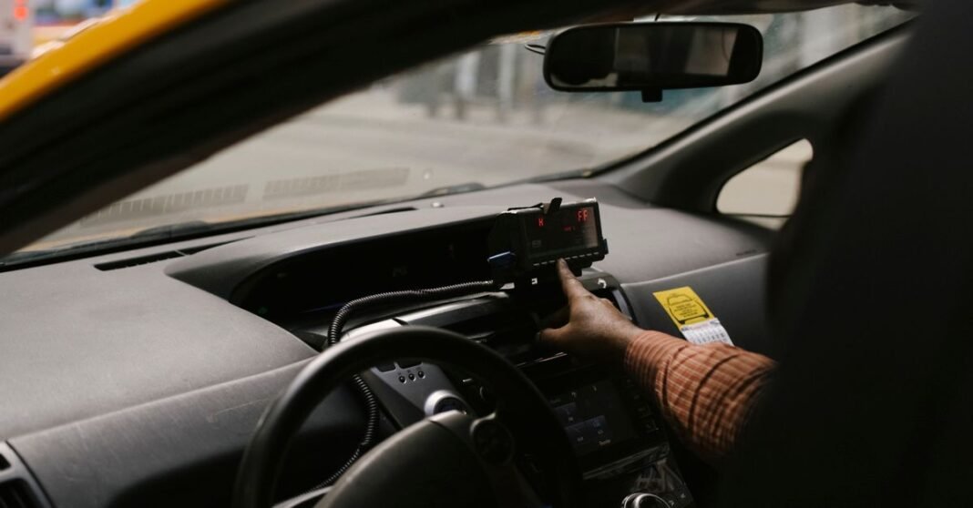 Anonymous ethnic male driver with steering wheel using GPS navigator to search direction for drive on street in city during work