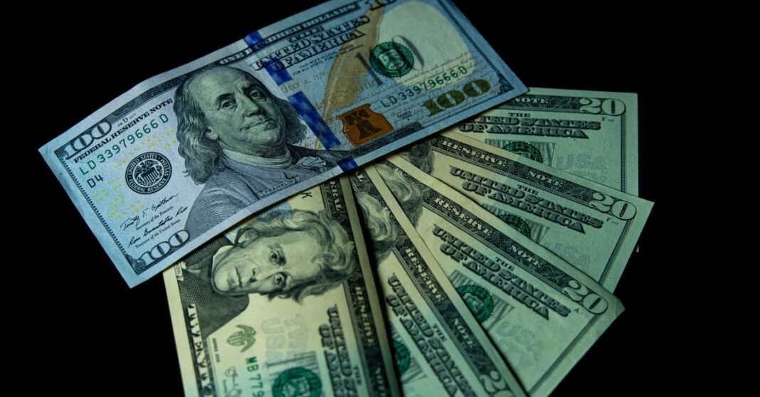 Close-up image of varied US dollar bills on a black background.