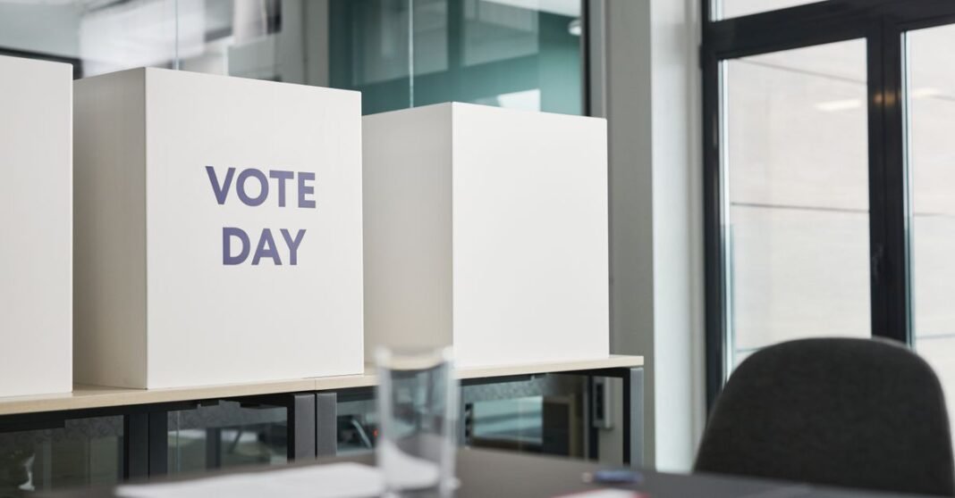 A modern office with voting booths labeled 'Vote Day' indicating election activity.