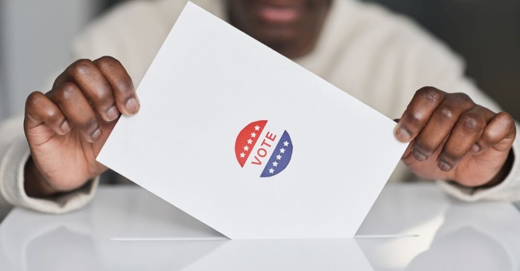 A voter placing a ballot into a box during an election. Focus on the act of voting.