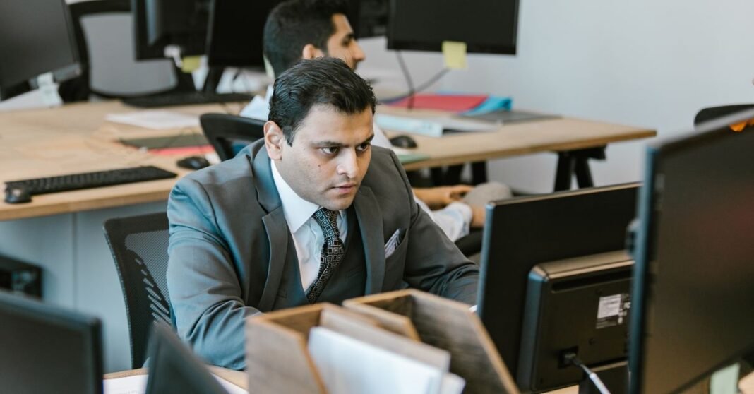 A dedicated businessman in a suit concentrating on work at a modern office desk.