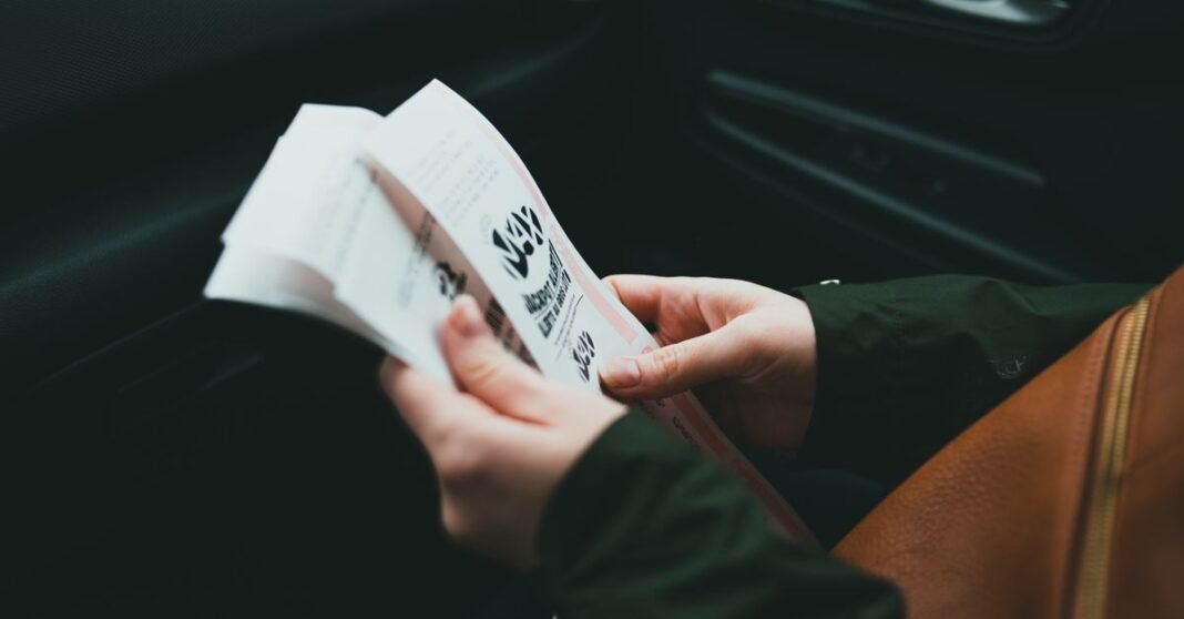 Close-up of hands holding a brochure inside a car, creating an intimate and focused scene.